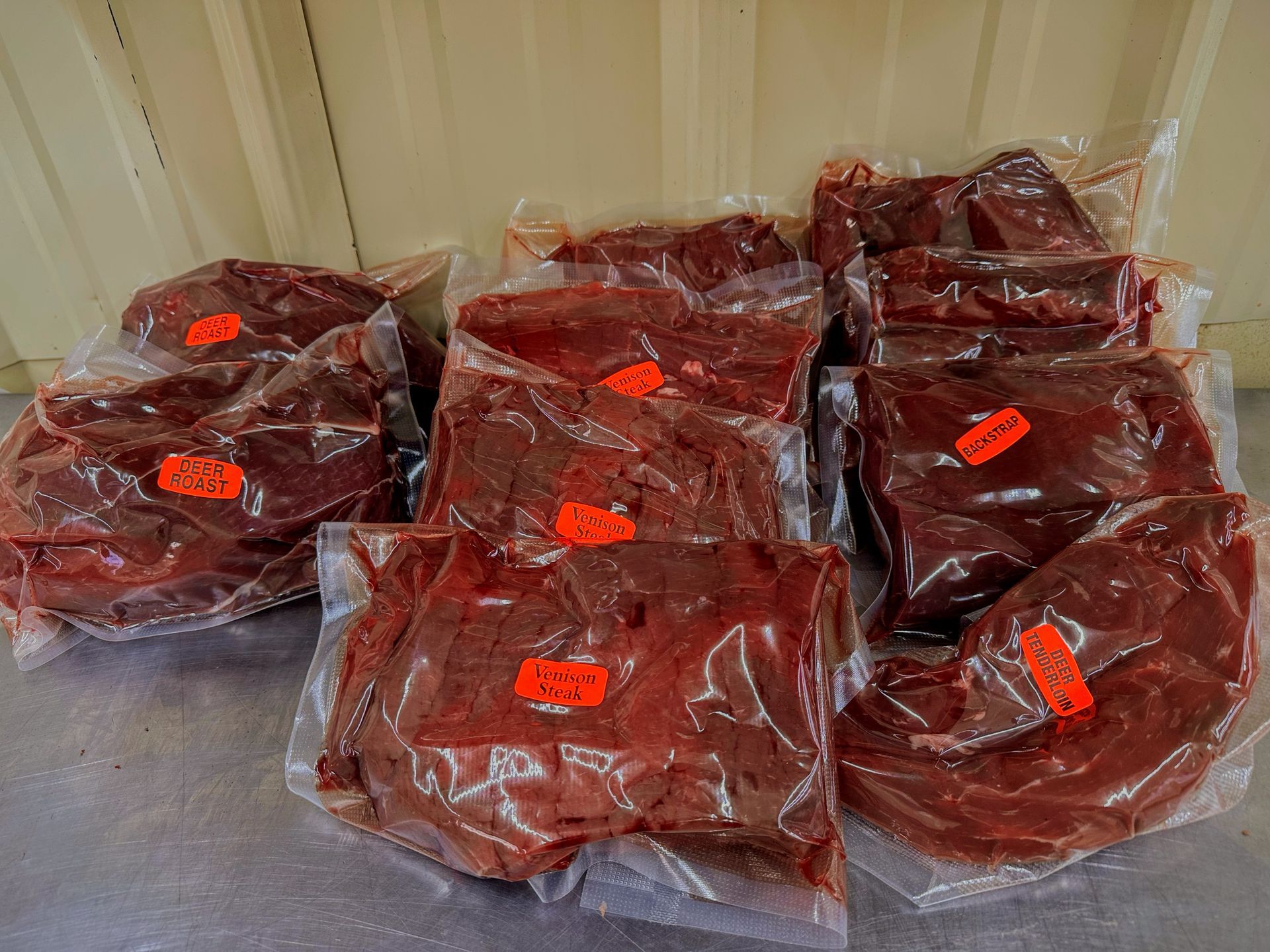 Vacuum-sealed, raw red meat on a light wooden cutting board.