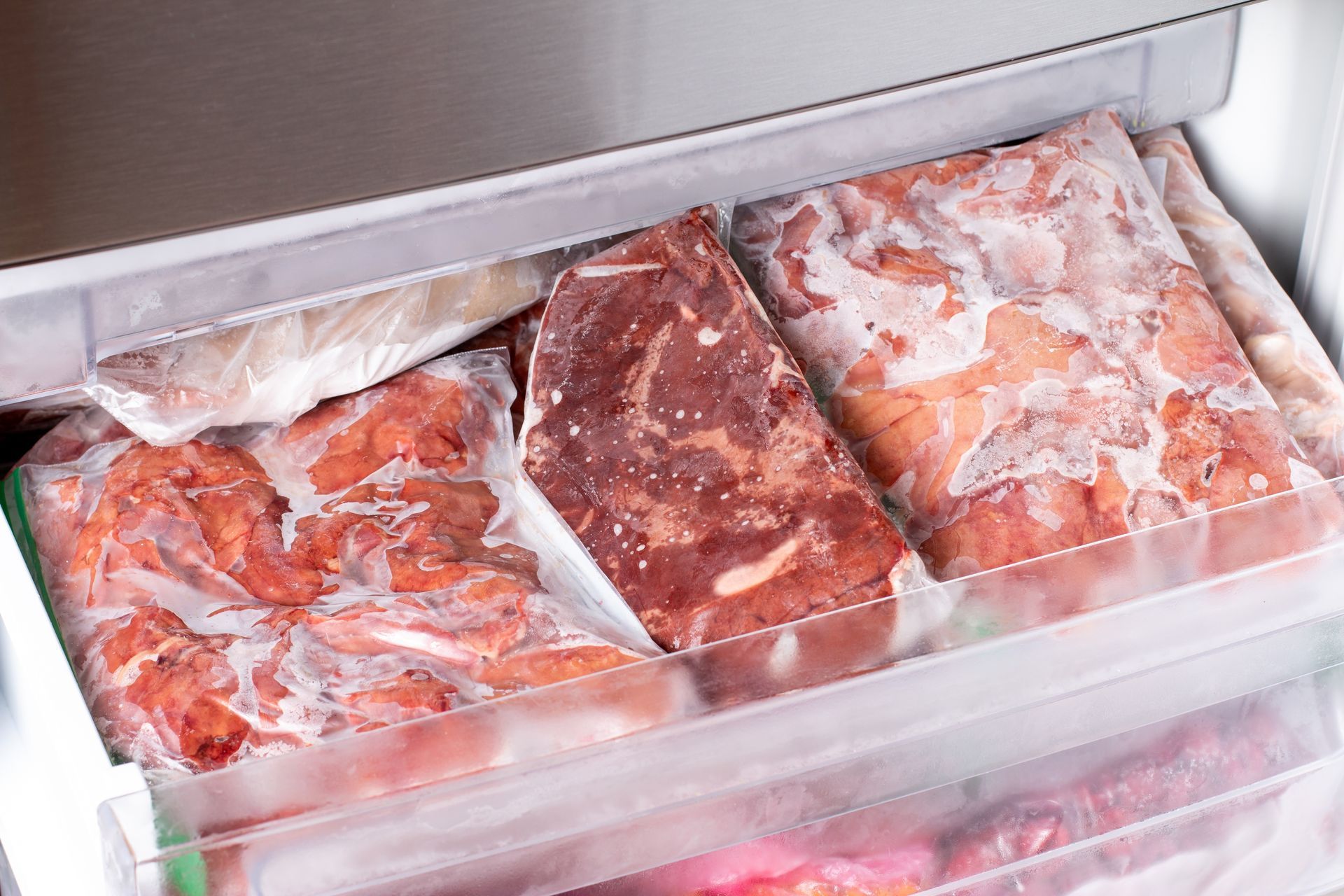 Frozen meat packages in a freezer drawer.