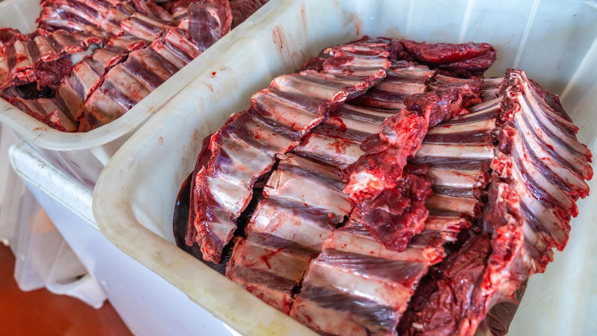 Raw, cut ribs in a white plastic container, ready for cooking.