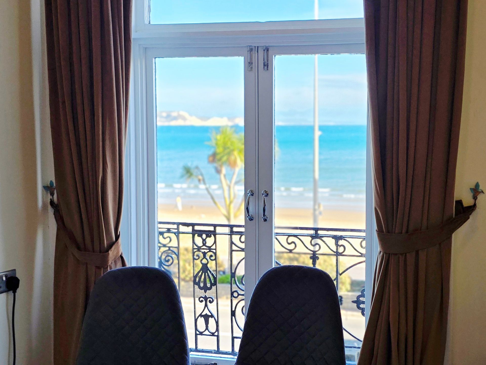 Bedroom with a bed, nightstand, lamps, and a window with an ocean view.