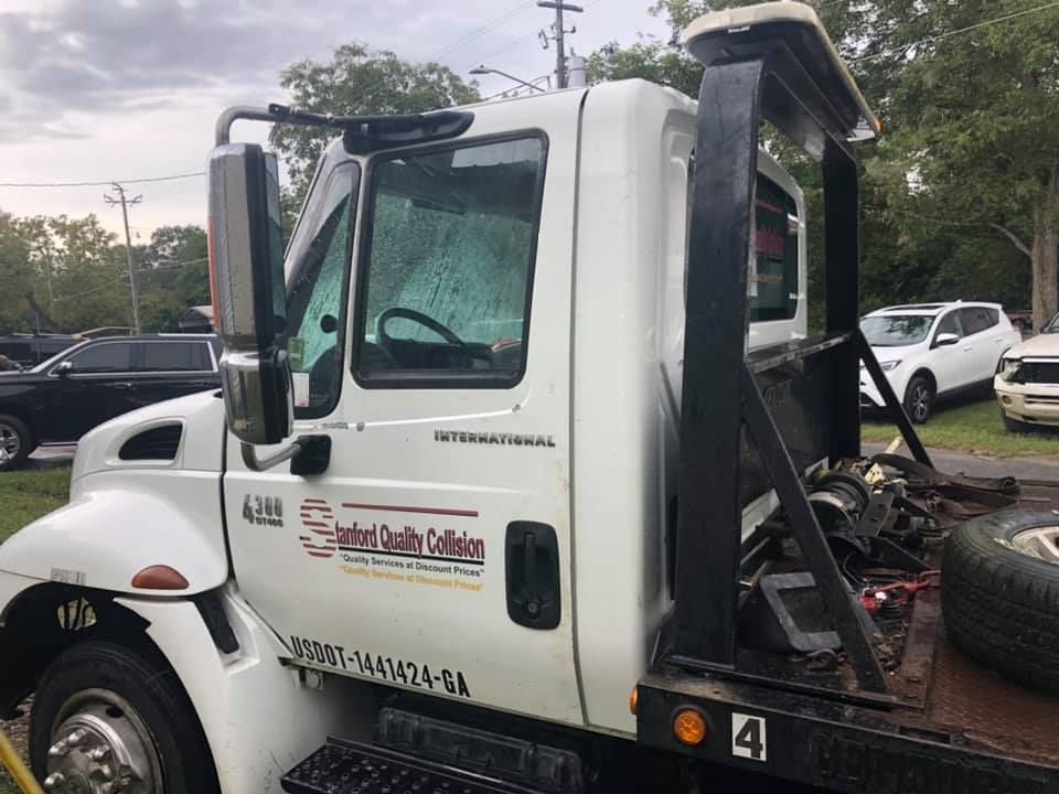 White tow truck with black framework parked outdoors. 
