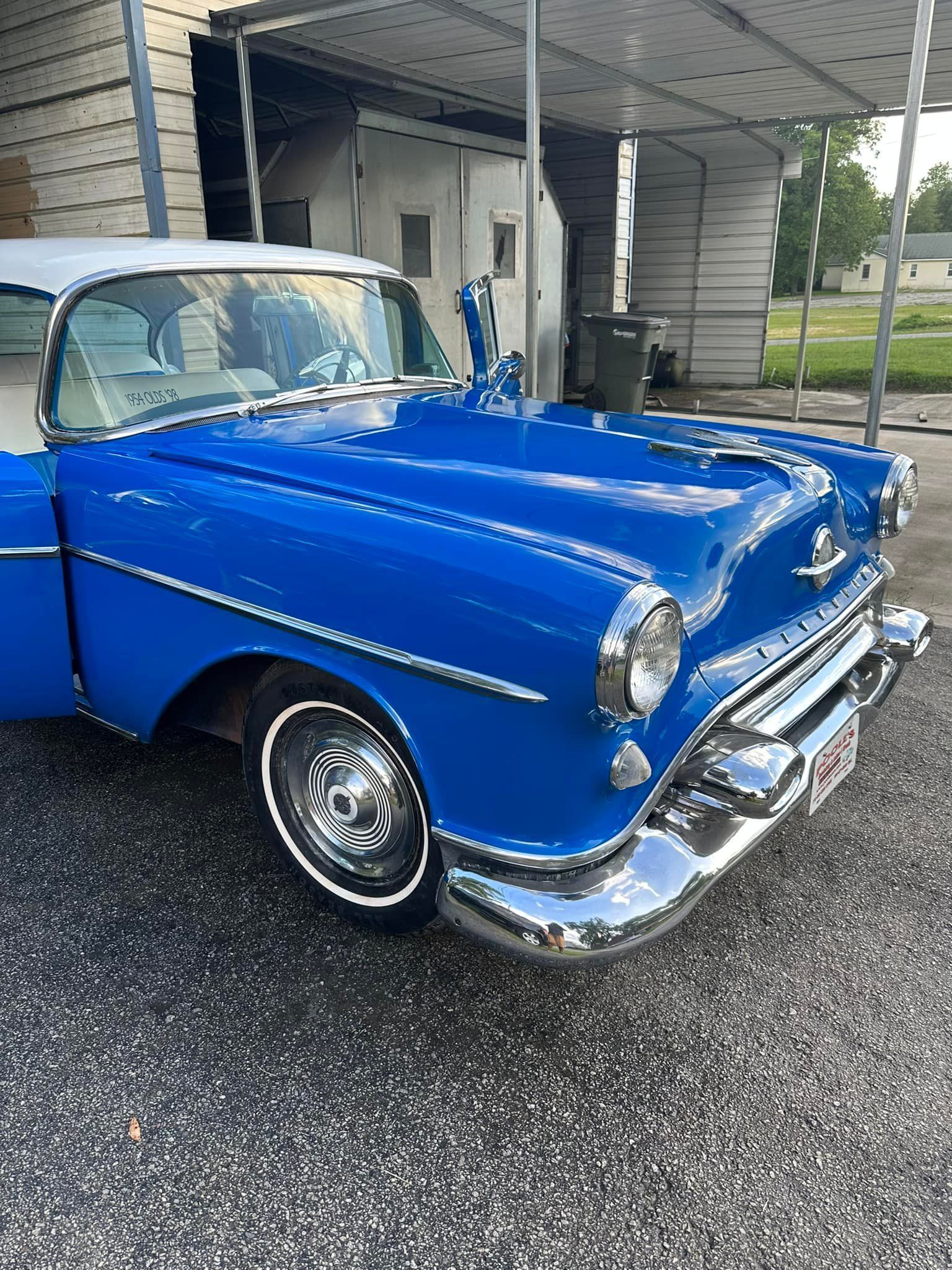 Blue and white classic car parked outside, chrome detailing, sunny day.