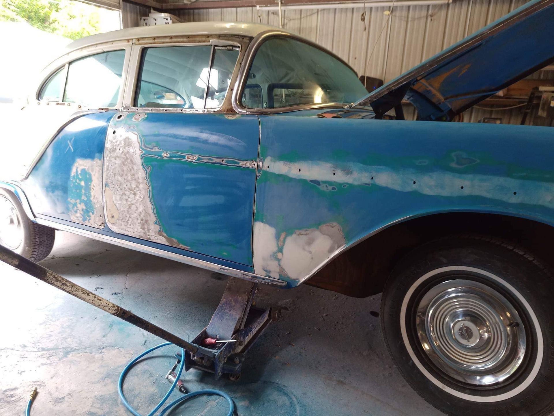 Blue classic car being restored, door and fender primed.