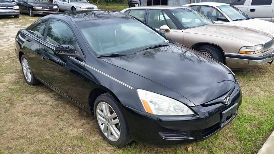 Black Honda Accord coupe parked on grass. Other cars visible in the background.