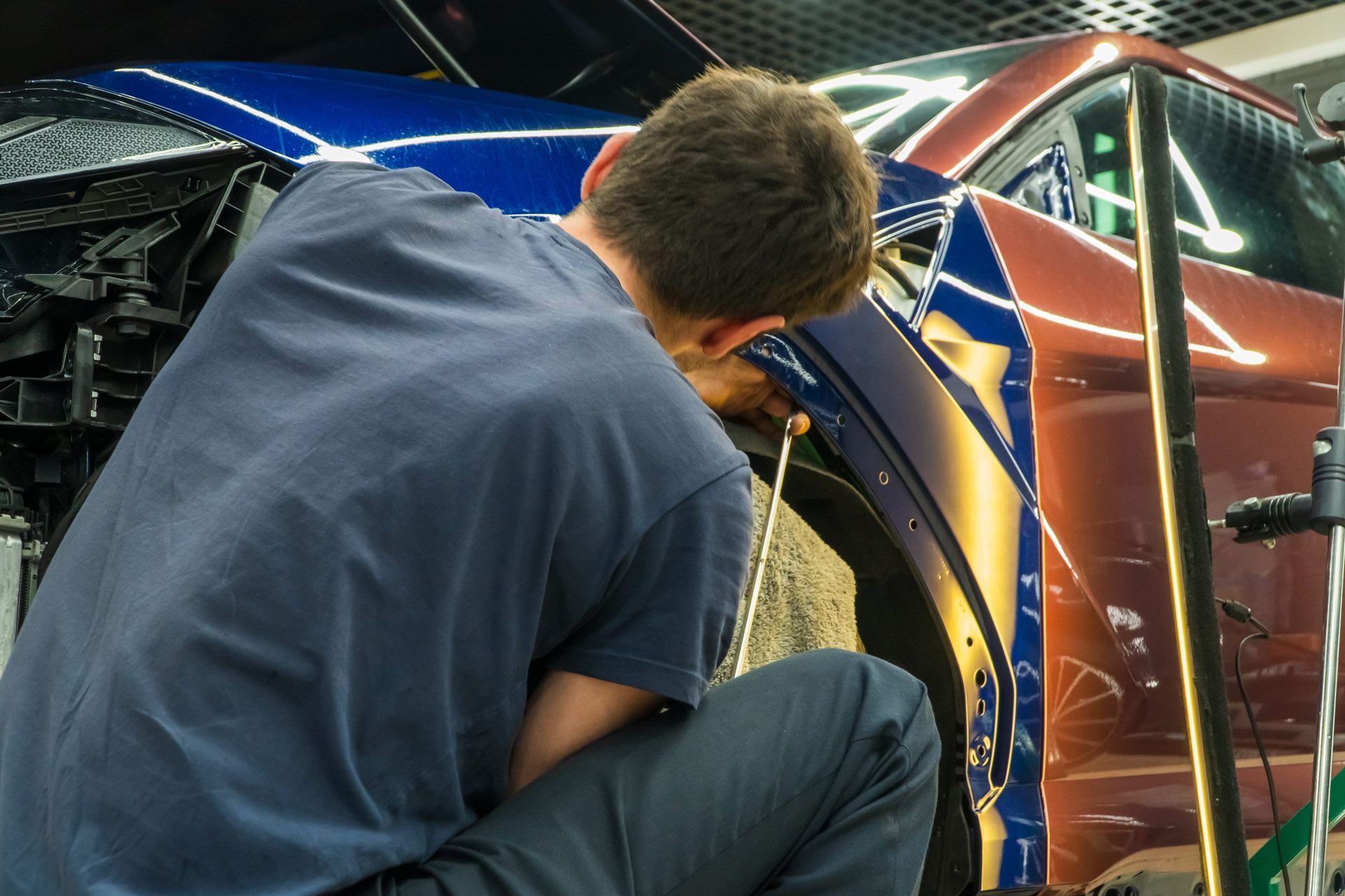 Person working on a car, applying blue and orange vinyl.