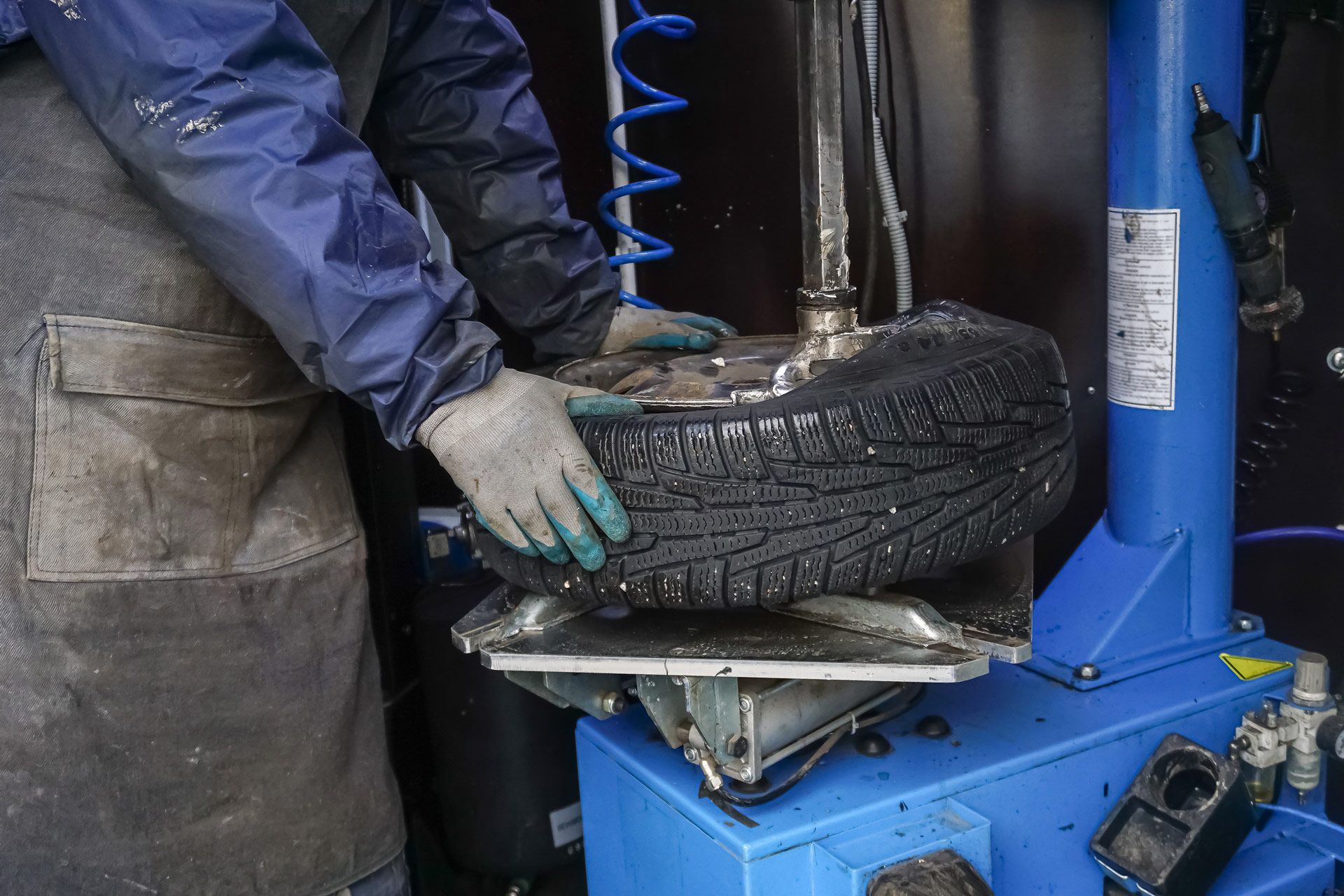 Person changing a tire with a machine. The tire is held by the machine. Hands are visible.