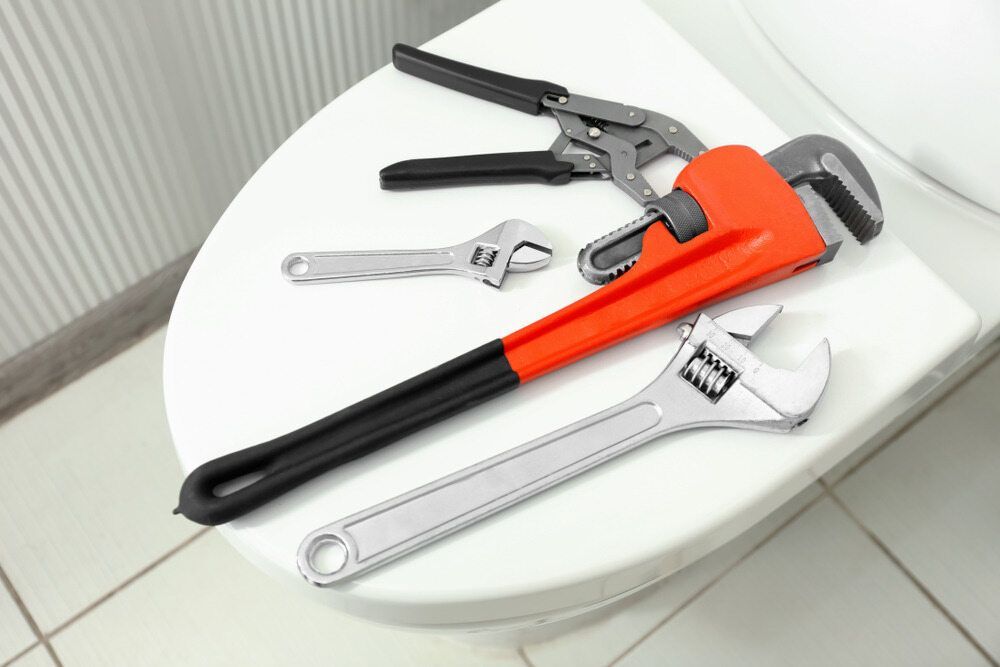 A Toilet Seat With A Wrench And Pliers On It — C.J Honeysett Plumbing In Wellington, NSW
