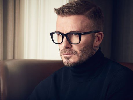 David Beckham trägt eine Brille und einen schwarzen Rollkragenpullover und sieht nachdenklich aus.