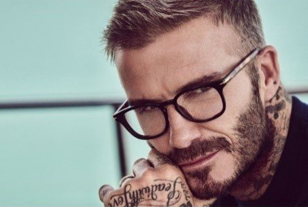 David Beckham trägt eine Brille, ruht mit dem Gesicht auf seiner Hand und blickt in die Kamera.