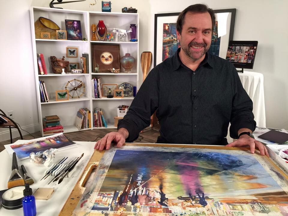 Watercolor Artist Paul Jackson Standing Over a Table of His Watercolor Art.