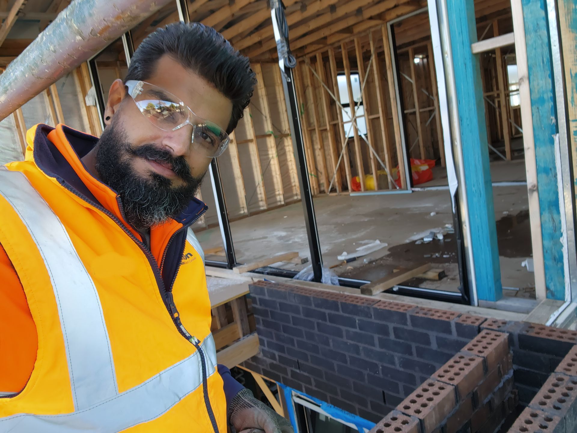 Two construction workers are standing in front of a building under construction.