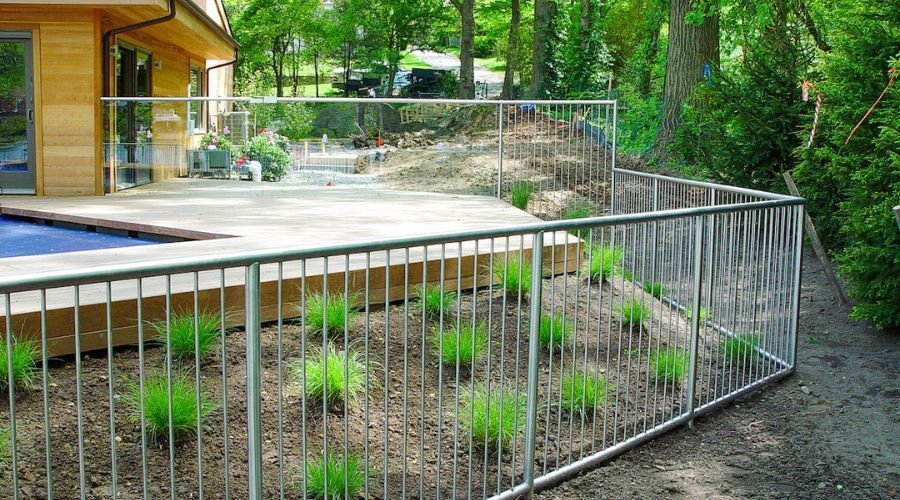 Minimalist metal pool fence preserving a wooded backyard view.