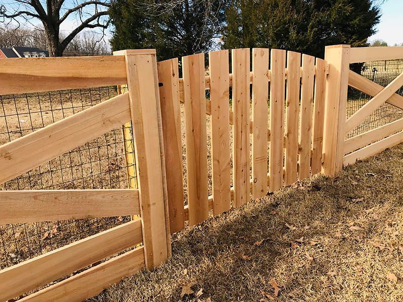 Wooden gate with a curved top, part of a cedar fence.