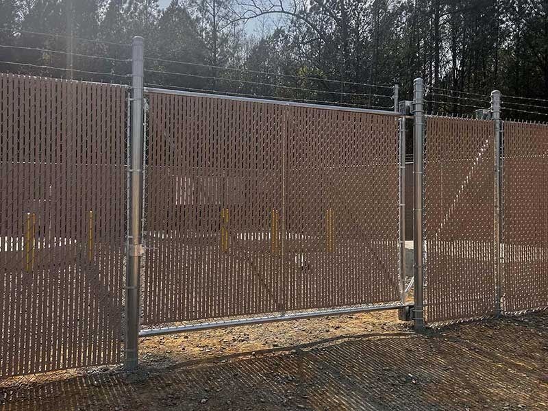 Brown privacy fence with barbed wire.