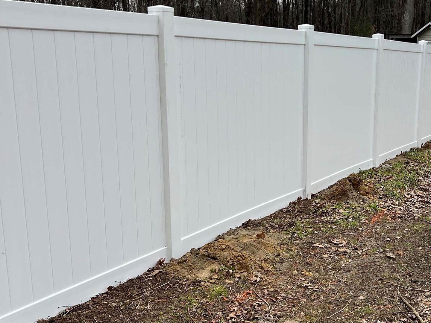 White vinyl privacy fence in a grassy area.