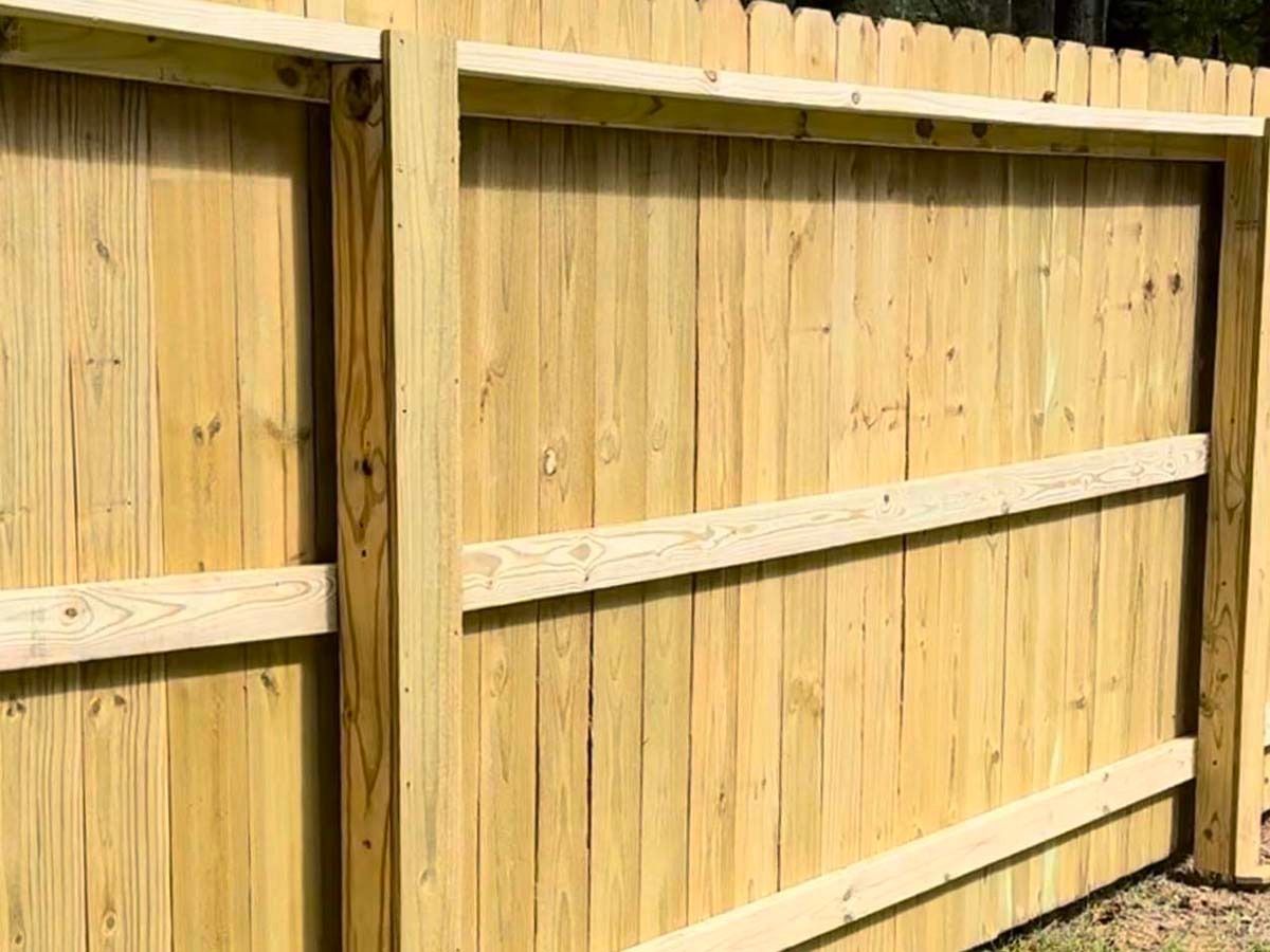 Wooden fence with vertical planks and horizontal supports in outdoor setting.