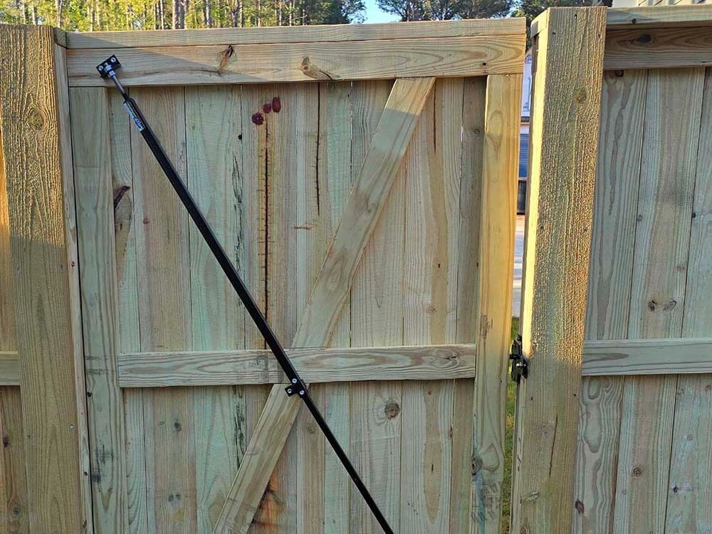Wooden gate with black diagonal brace and automatic closer.