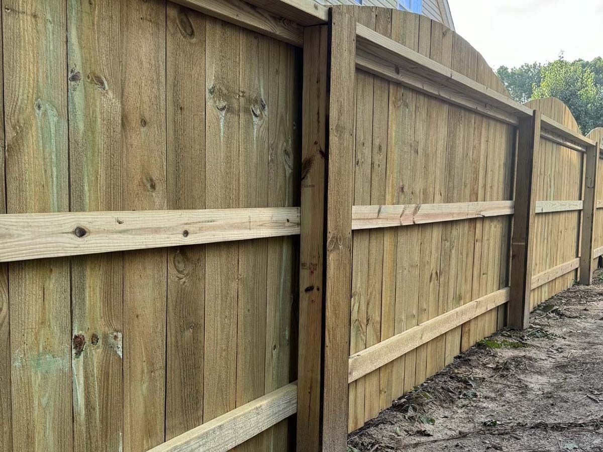 Wooden fence with a weathered, light brown appearance, outdoors.