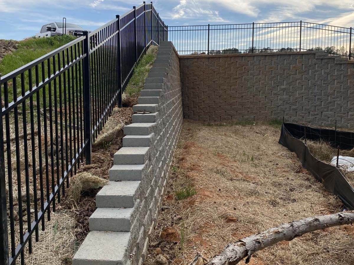 A black fence and concrete steps on a hillside.