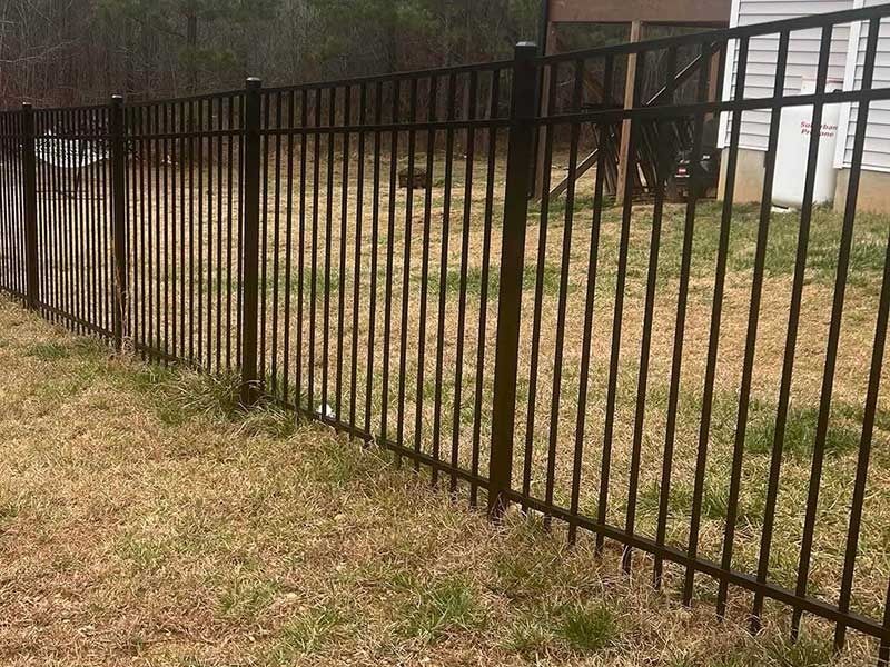 Black metal fence in a grassy yard, possibly a residential area.