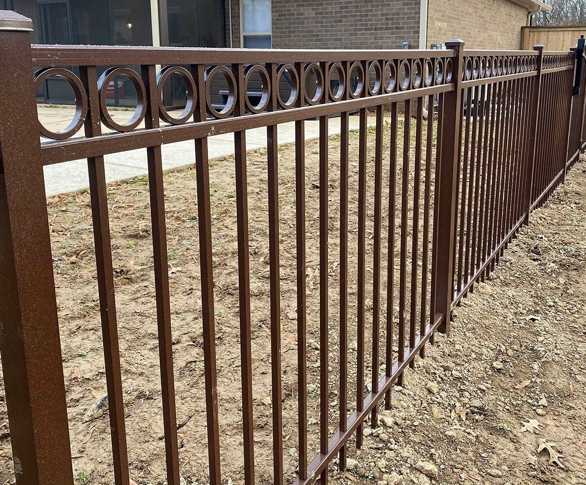 Brown metal fence with circular and arched design.