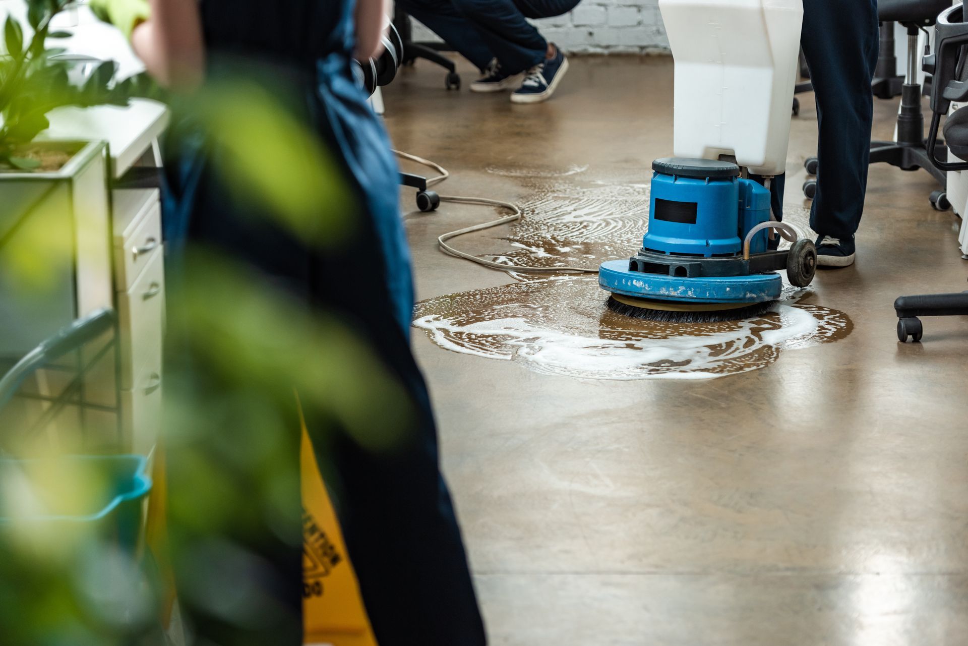 A person is cleaning a floor with a machine in an office.