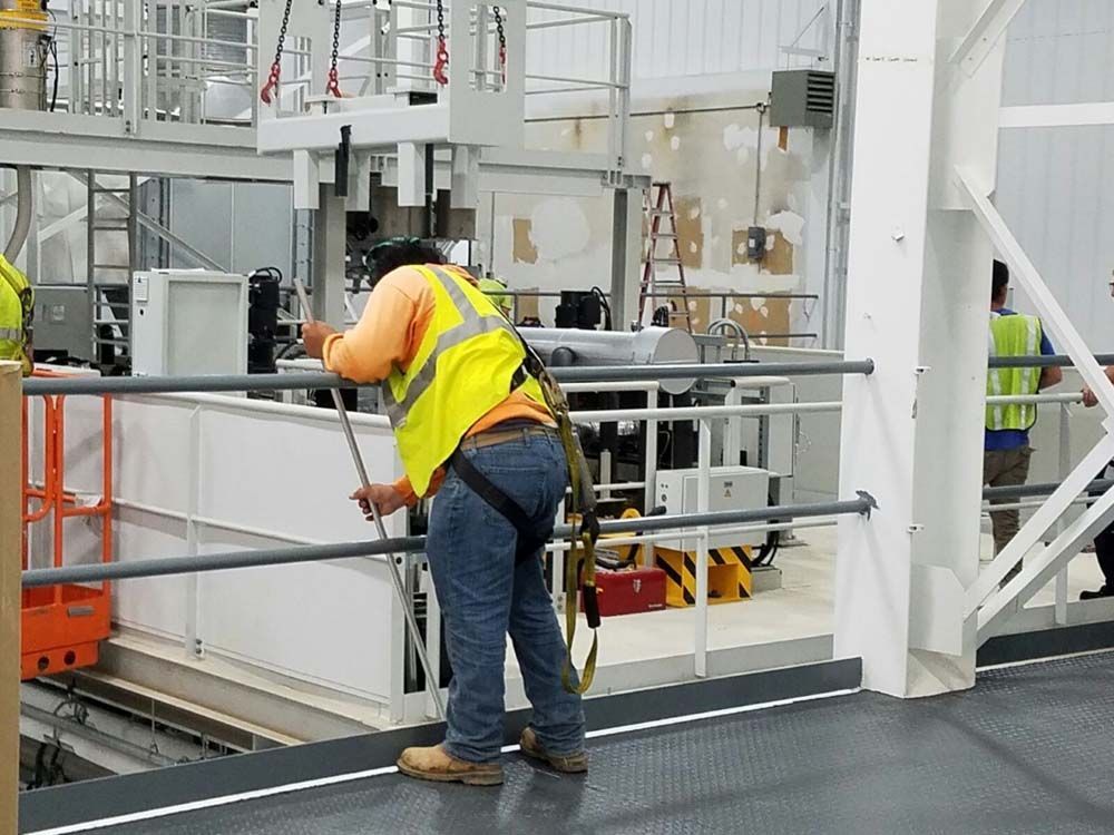 A man in a yellow vest is working on a machine