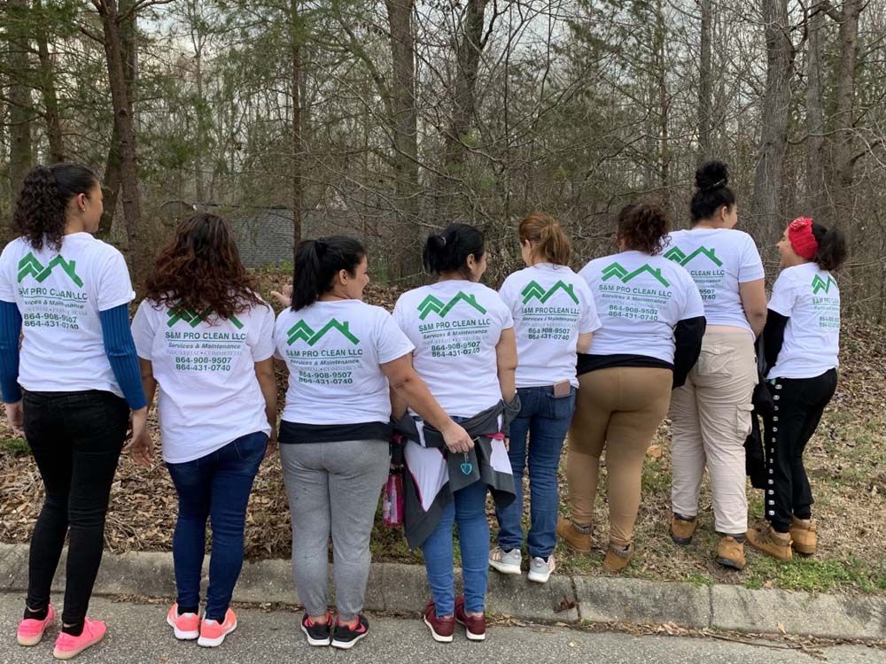 A group of women are standing next to each other in front of a forest.