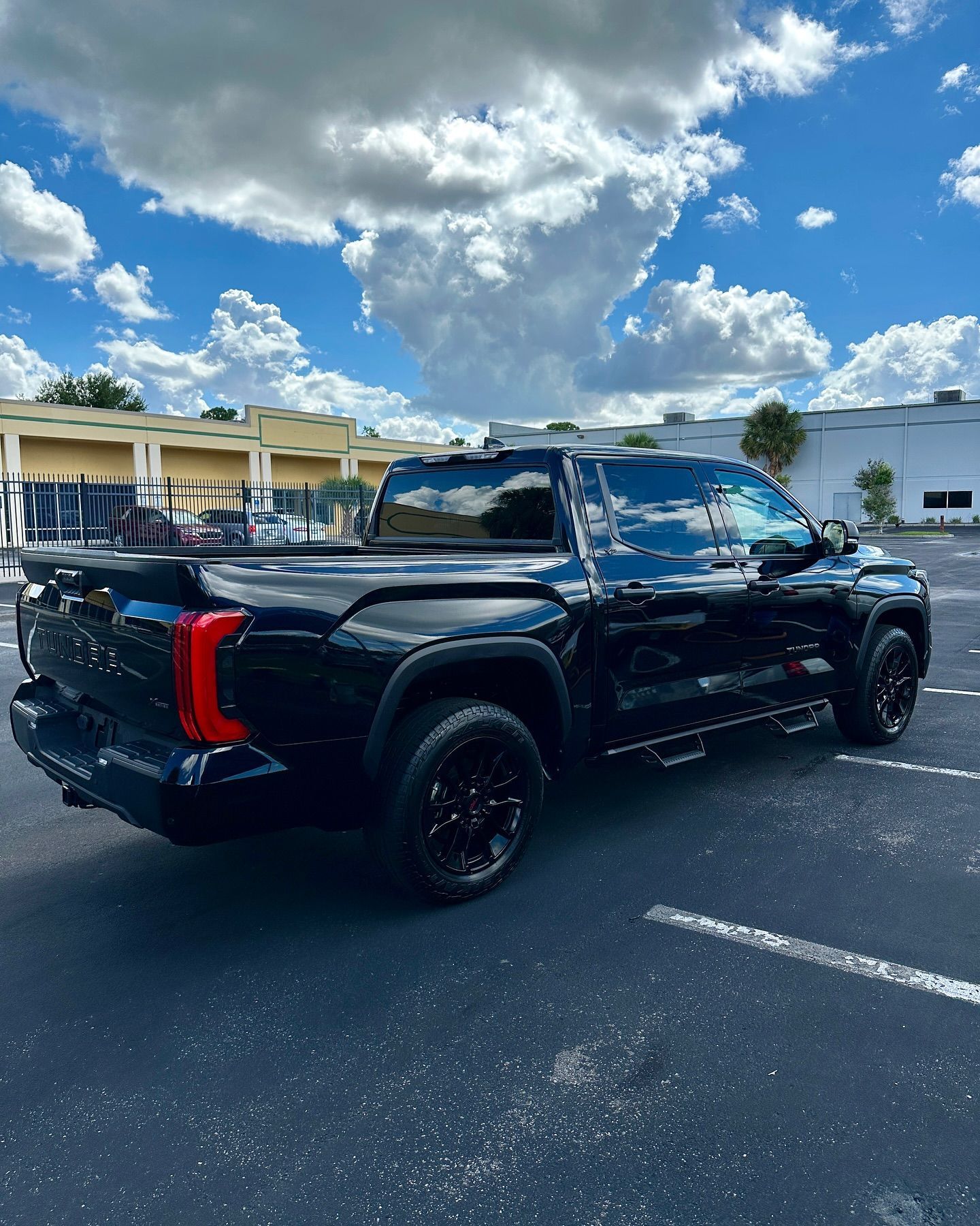 A black truck is parked in a parking lot.