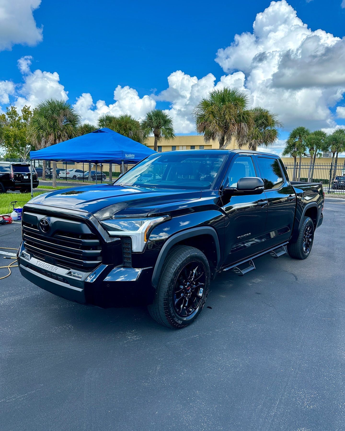 A black toyota tundra is parked in a parking lot next to a blue tent.