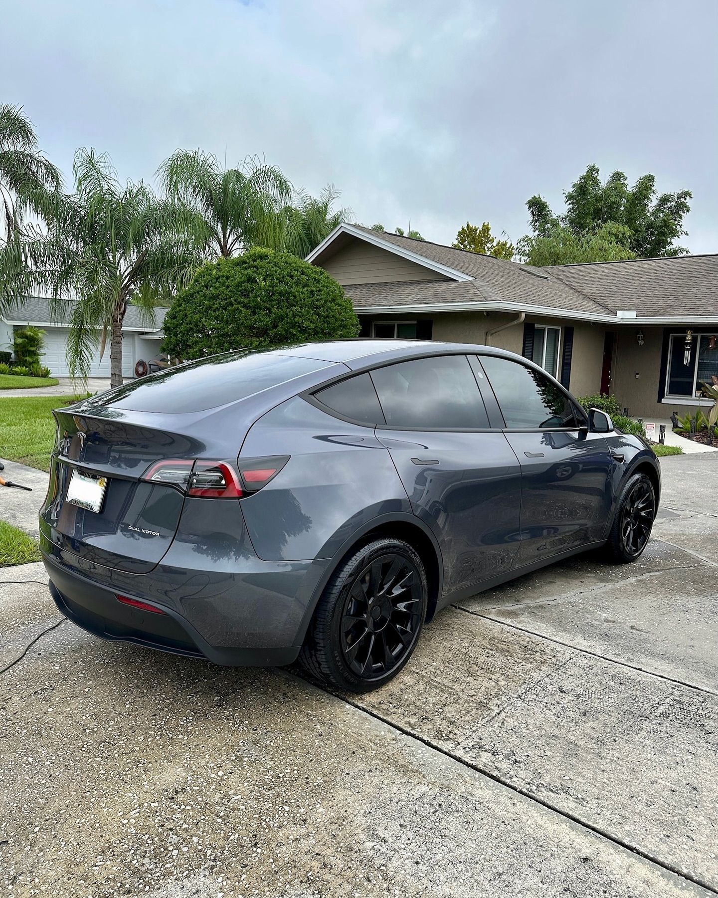 A tesla model y is parked in front of a house.