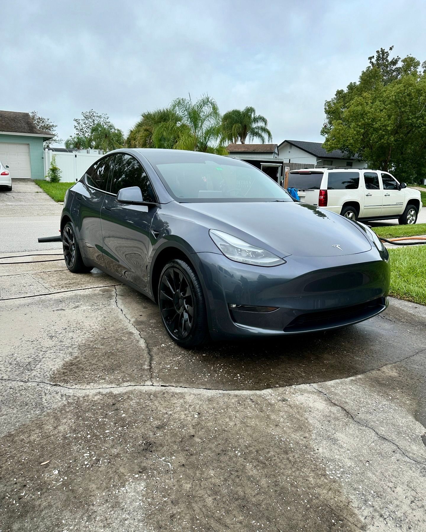 A tesla model y is parked in a driveway next to a house.