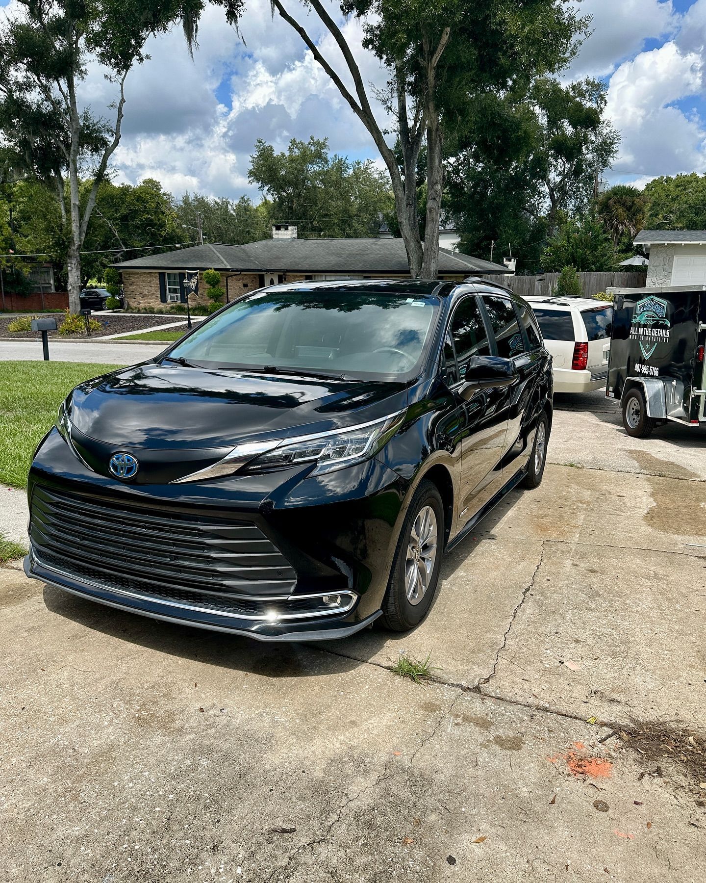 A black toyota sienna is parked on the side of the road in front of a house.