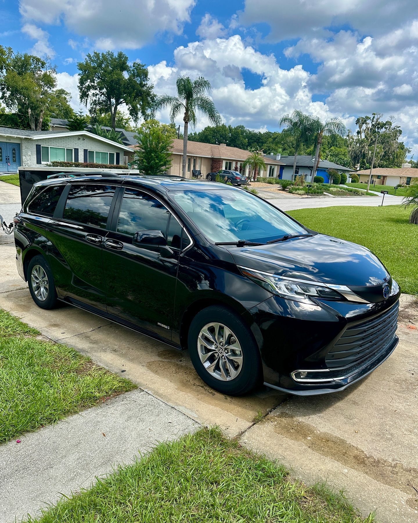 A black minivan is parked on the side of the road in a residential neighborhood.
