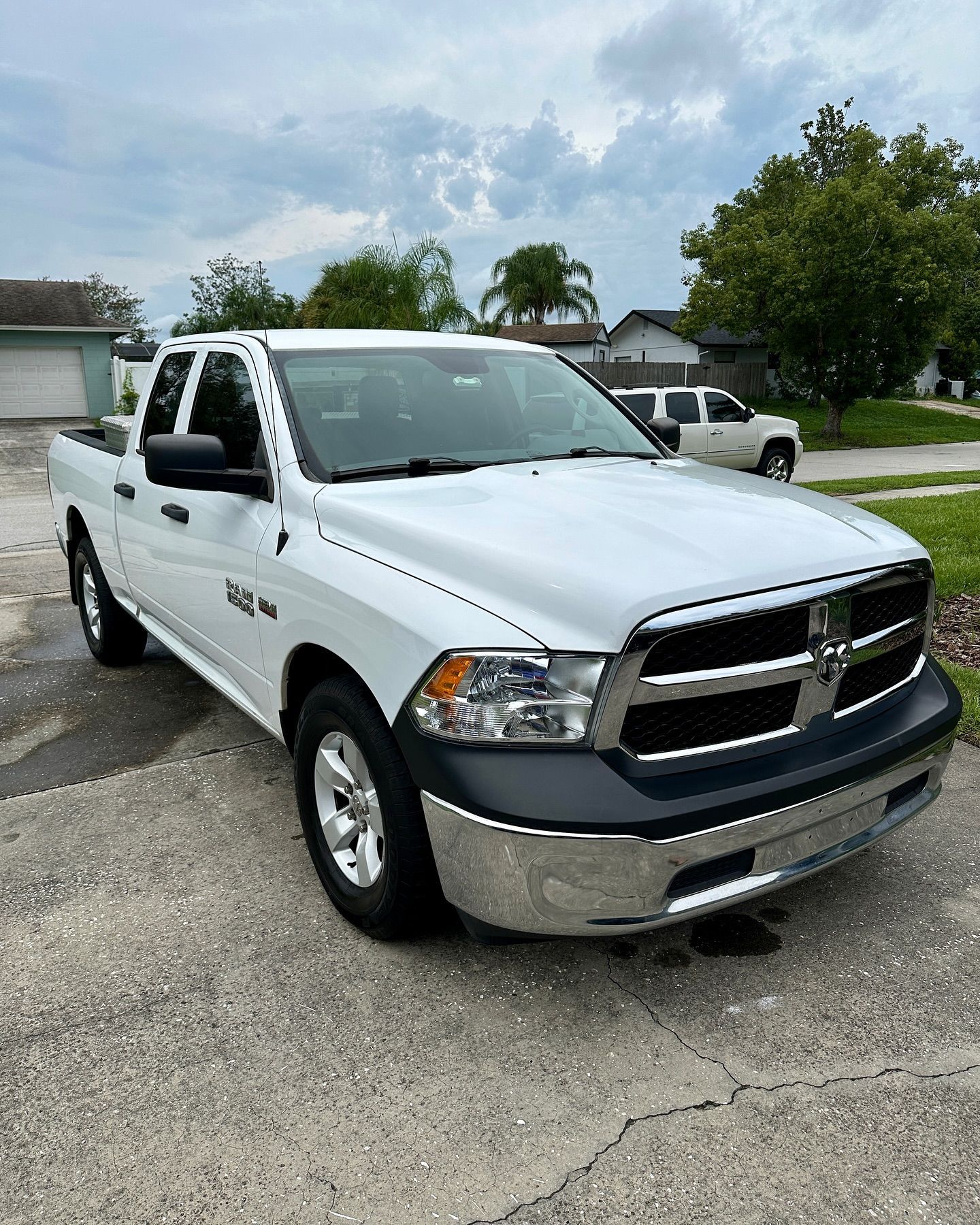 A white dodge ram truck is parked in a driveway in front of a house.