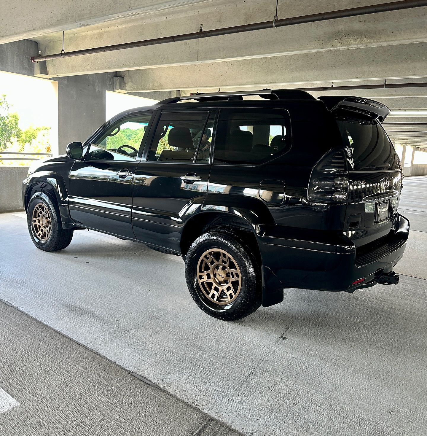A black suv is parked under a bridge in a parking garage.