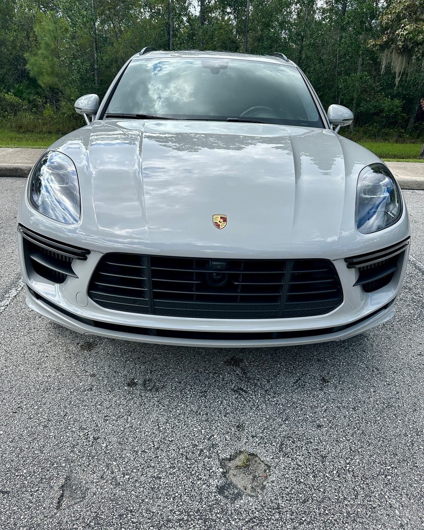 A white porsche macan turbo is parked on the side of the road.