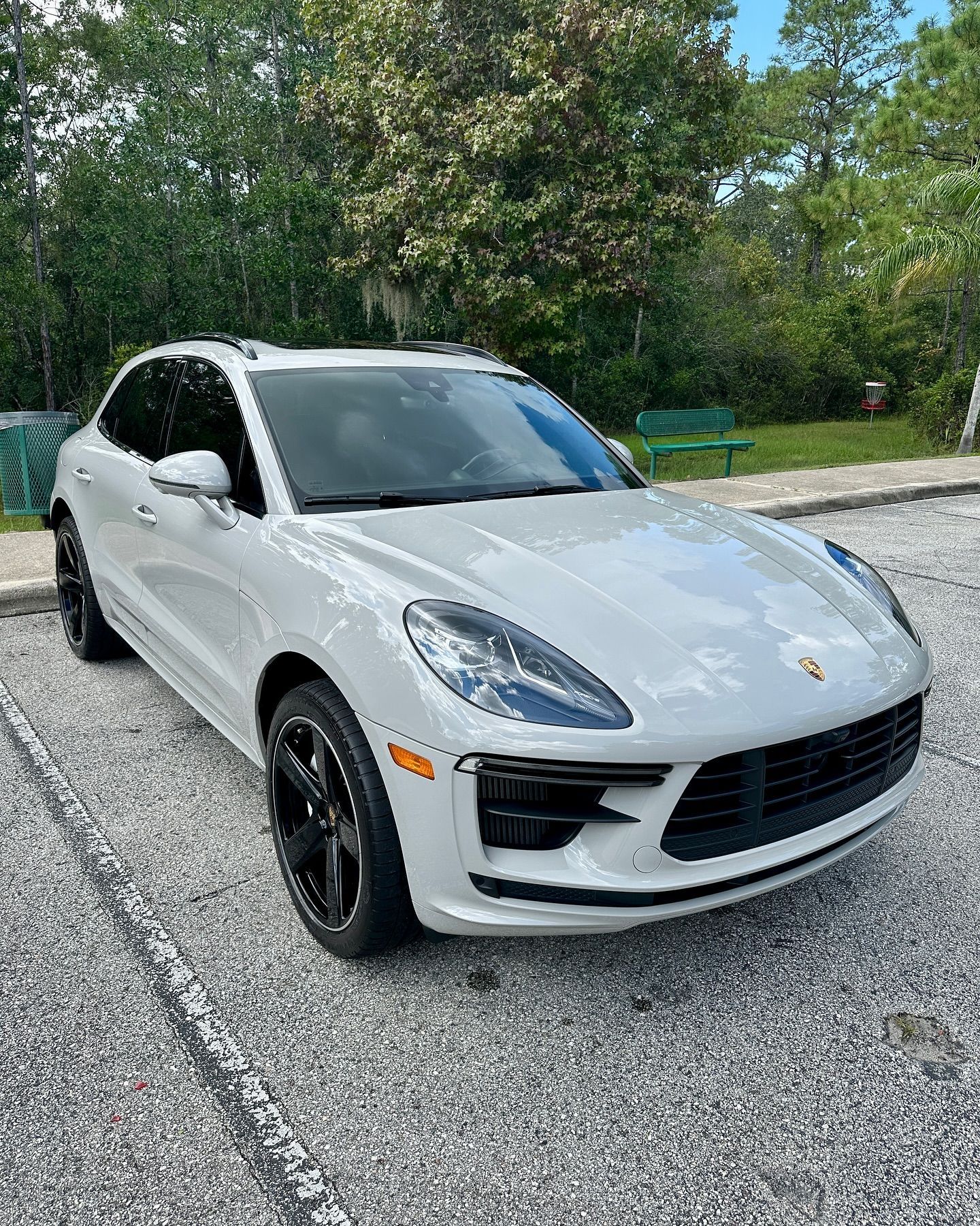 A white porsche macan is parked in a parking lot.