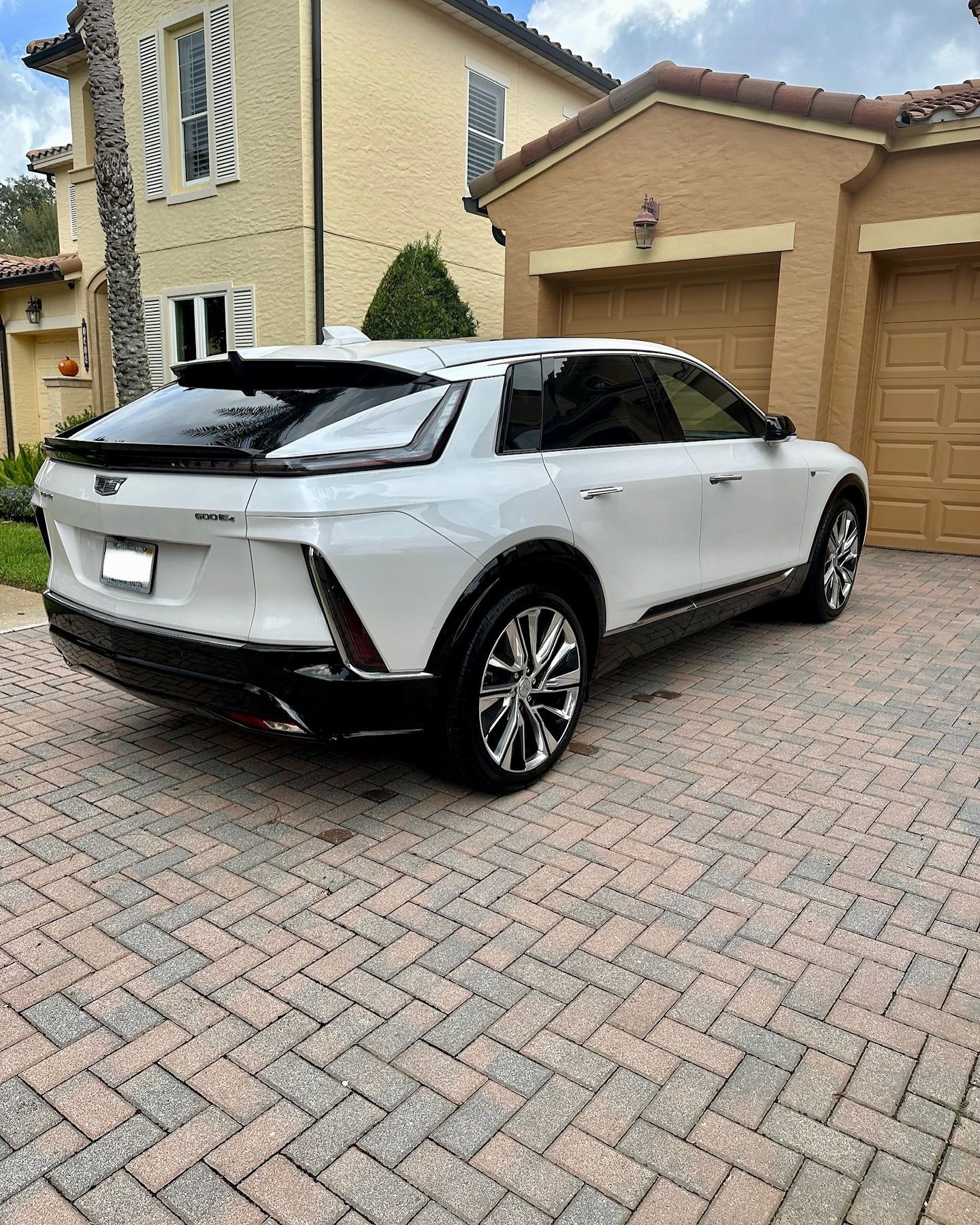 A white car is parked in a driveway in front of a house.