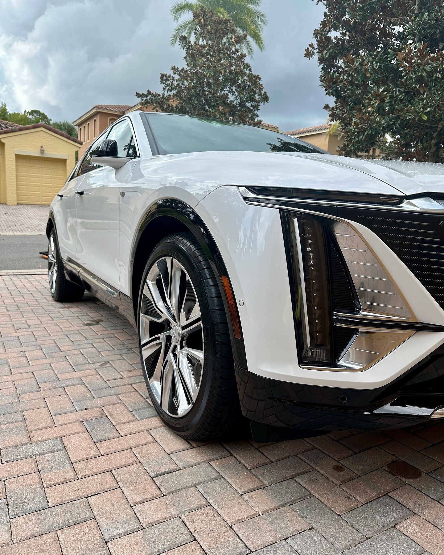 A white car is parked on a brick driveway.