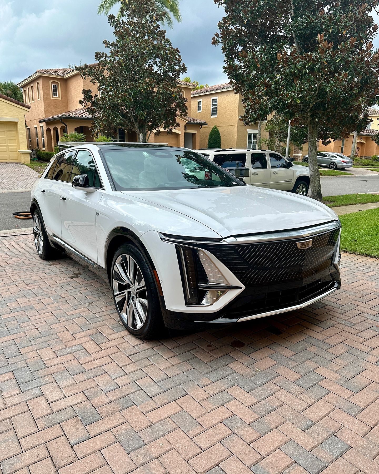 A white car is parked on a brick driveway in front of a house.