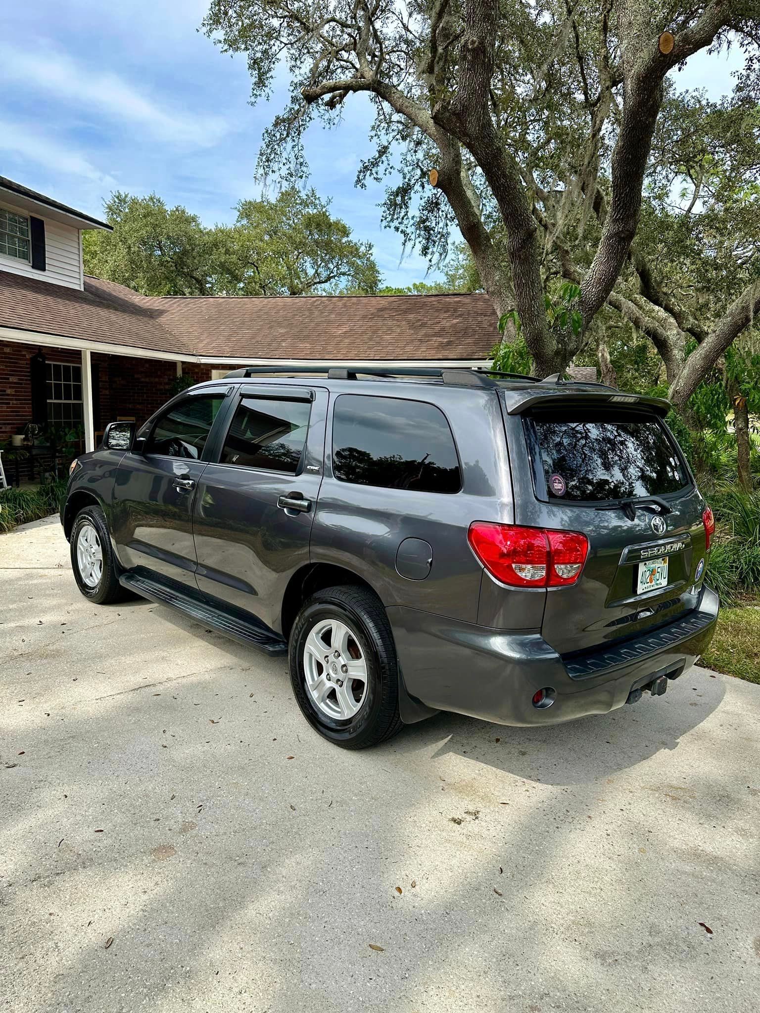 A toyota sequoia is parked in a driveway in front of a house.