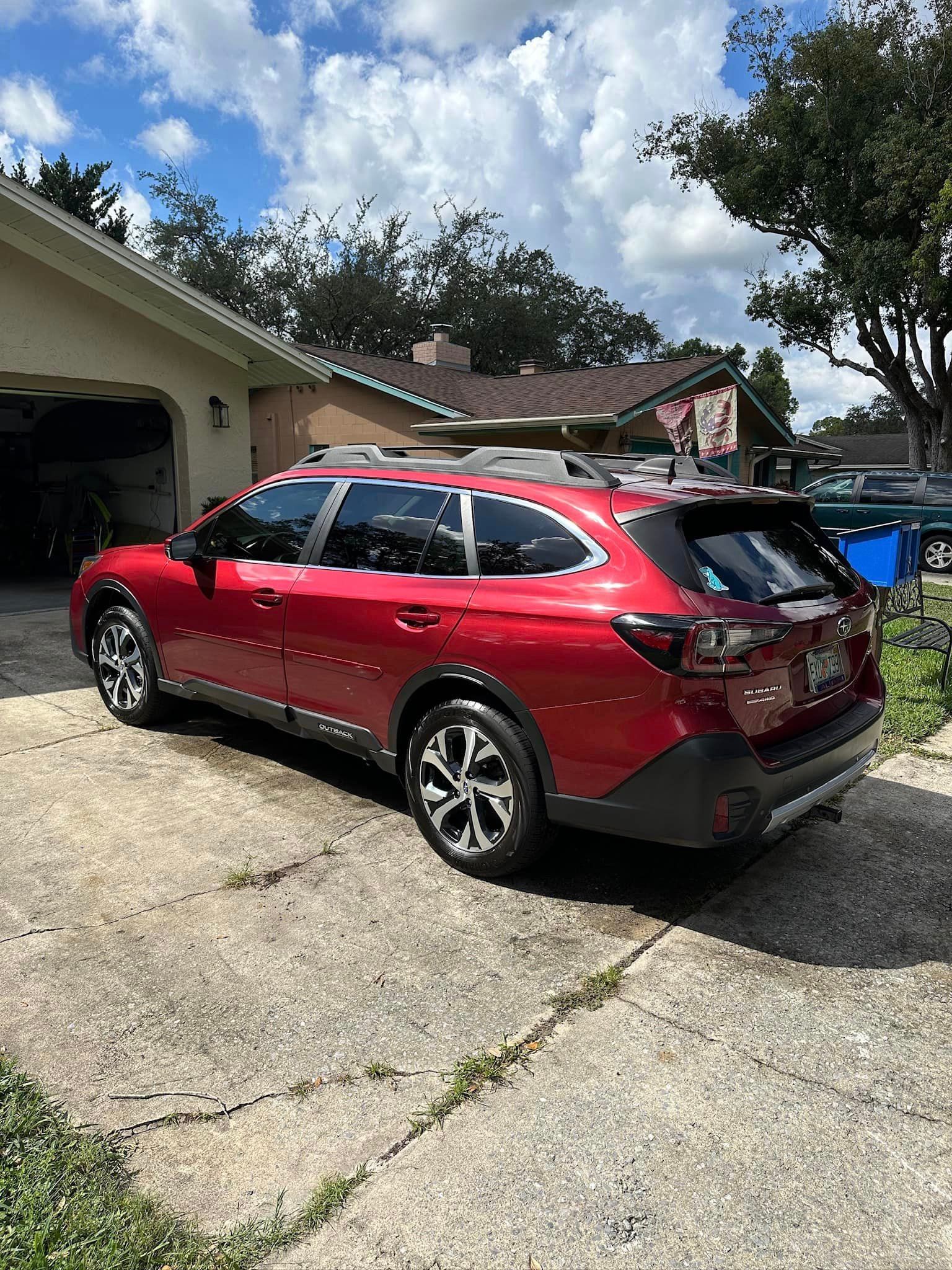 A red suv is parked in a driveway in front of a house.