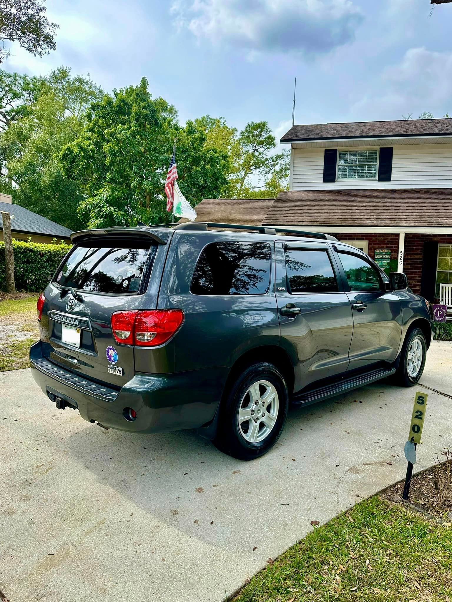 A toyota sequoia is parked in a driveway in front of a house.