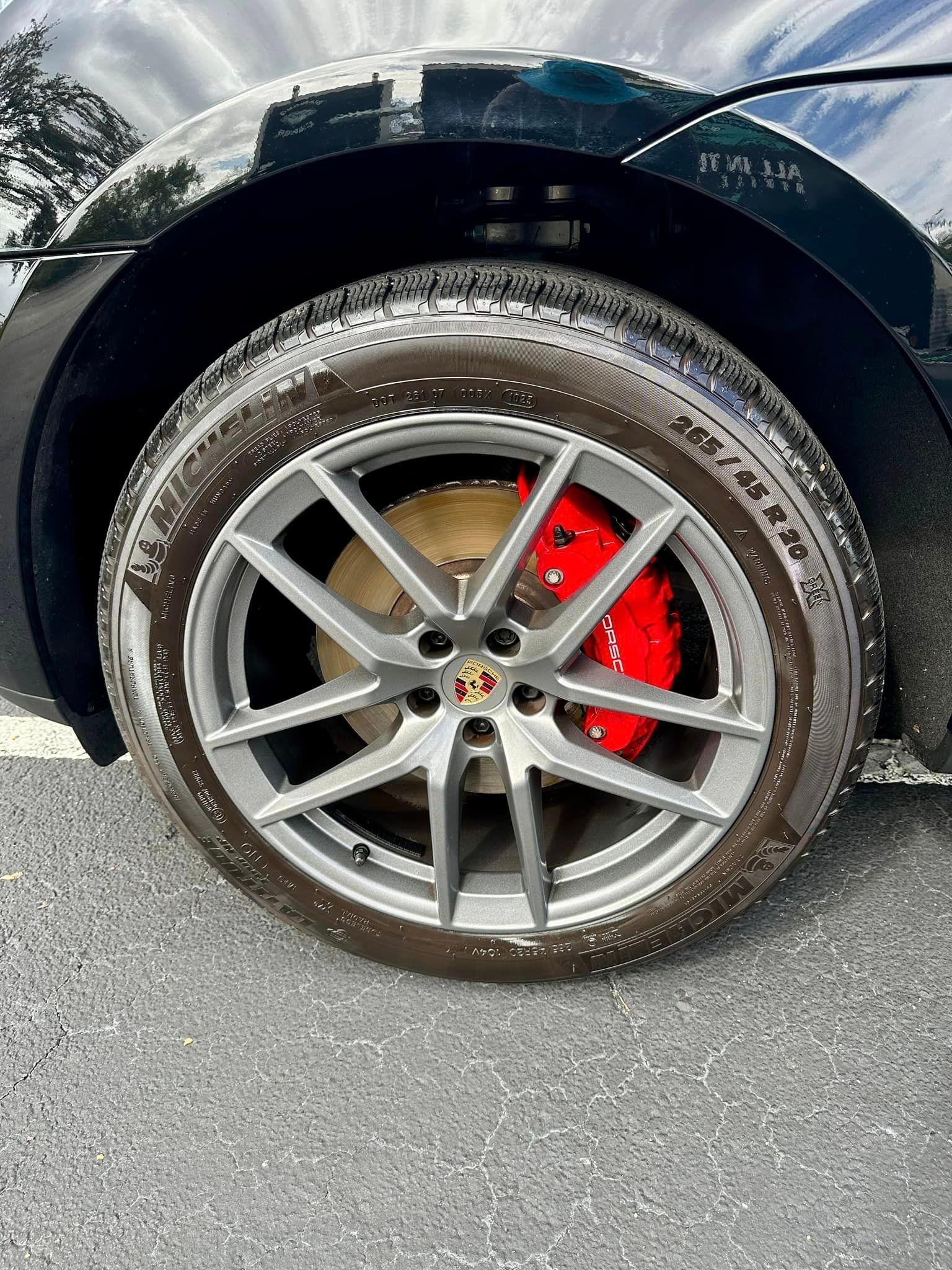 A close up of a car wheel with a red brake caliper.