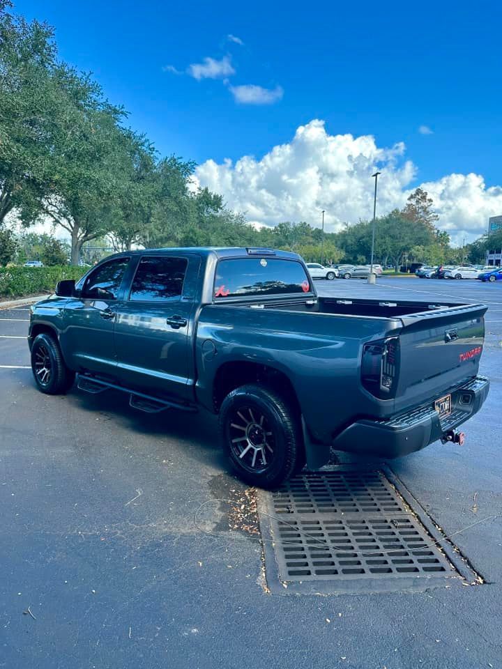 A green toyota tundra is parked in a parking lot.