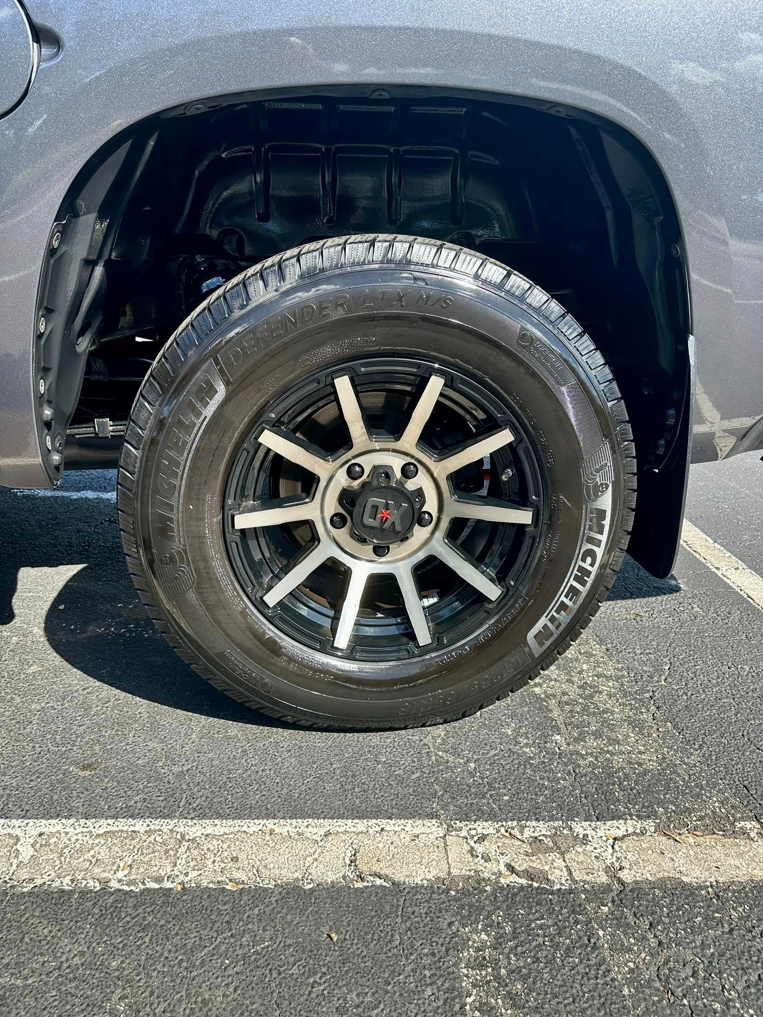 A close up of a tire on a truck in a parking lot.