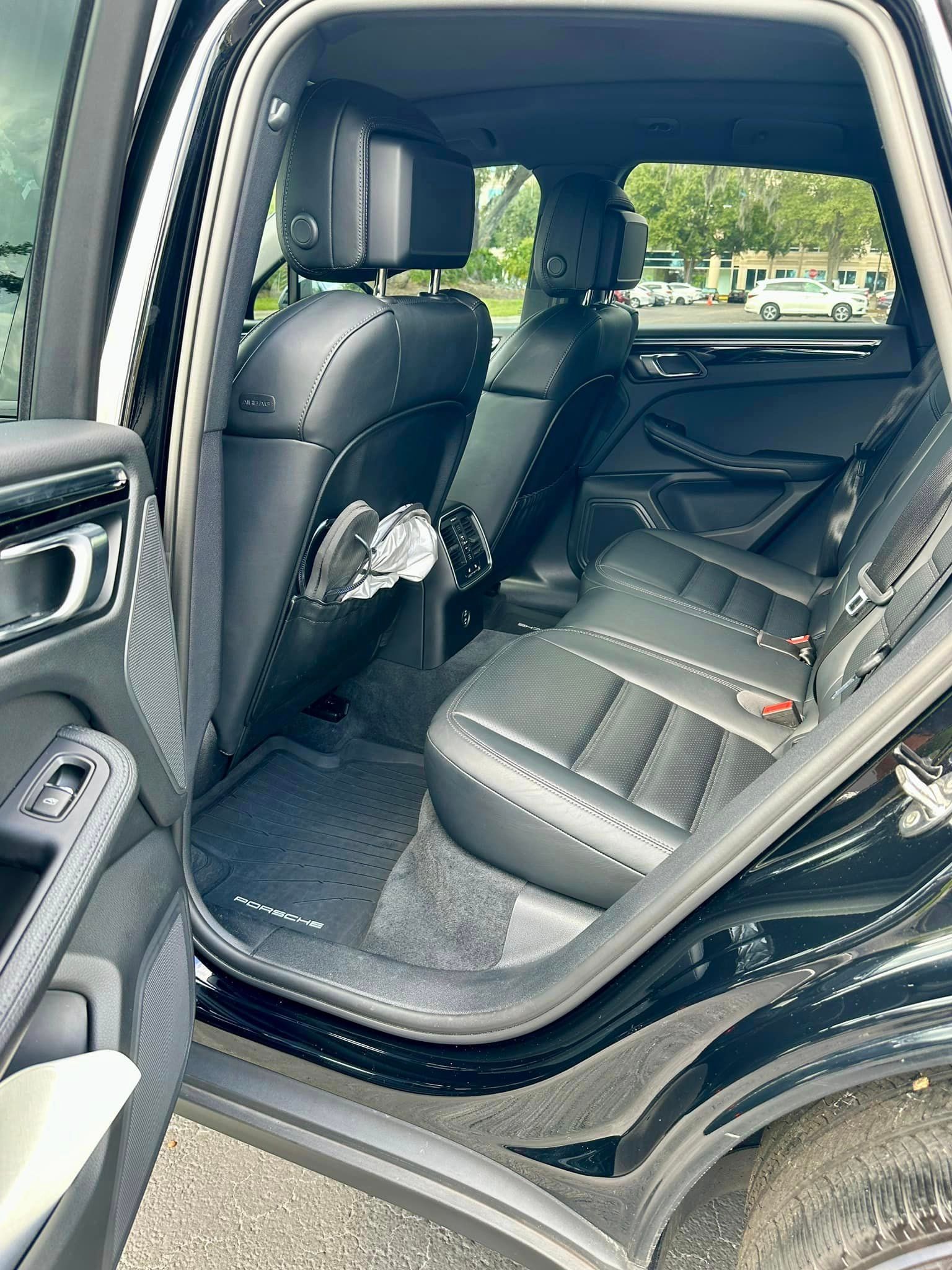 The back seat of a black car with the door open.