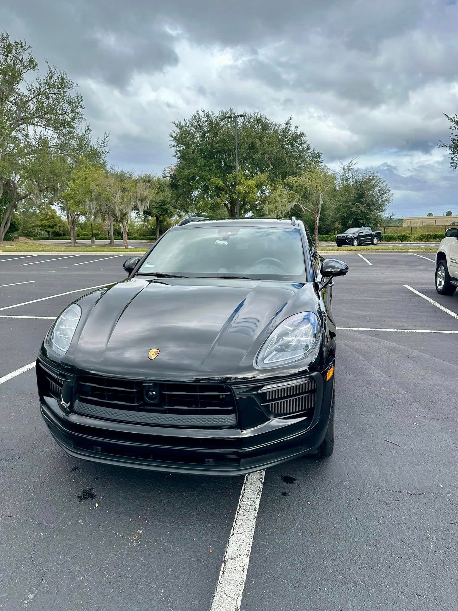 A black porsche macan is parked in a parking lot.