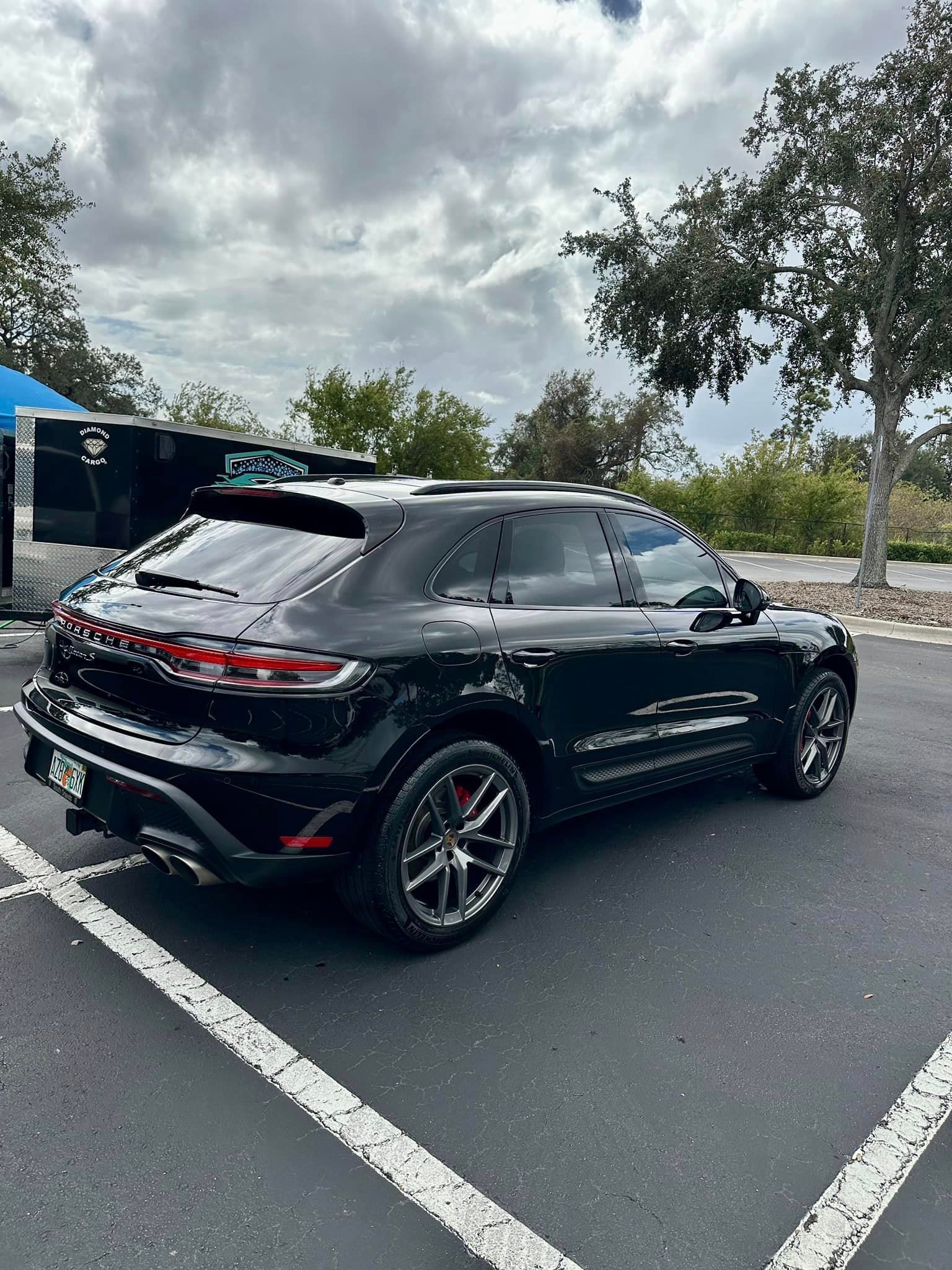 A black porsche macan turbo is parked in a parking lot.